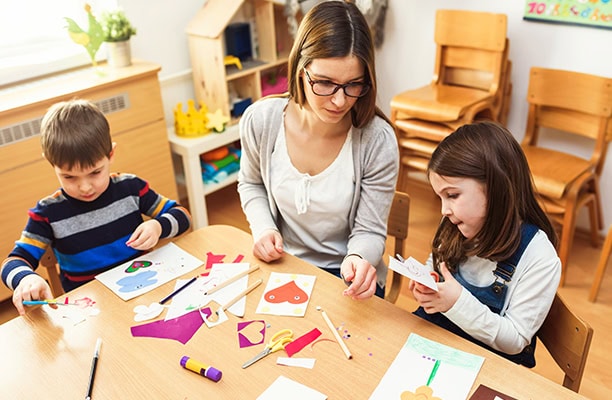 Teacher Helping Children Arts And Crafts